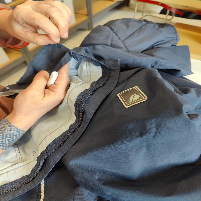 Sömmerska som jobbar med att byta dragkedja på en jacka Byta av dragkedja på en jacka