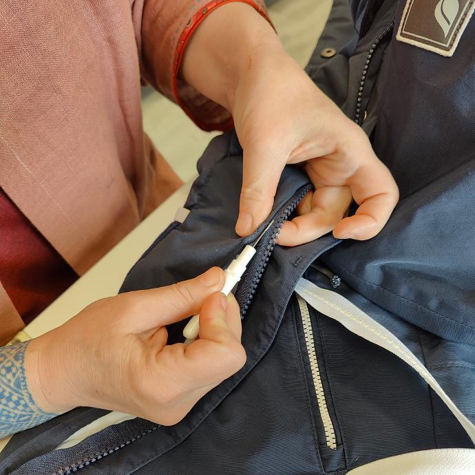 Skräddare som sprättar bort en dragkedja laga trasig dragkedja